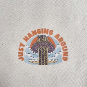 Detailaufnahme eines Jutestoffs mit Druck von Hängender Achterbahn, Farben und Textur sichtbar.